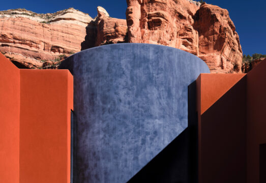 Blue circular grotto with red rock in view behind in Sedona, AZ