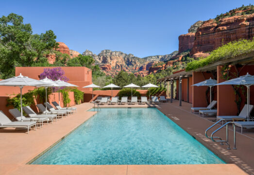Pool view at Mii amo with white umbrellas and red rocks in the distance