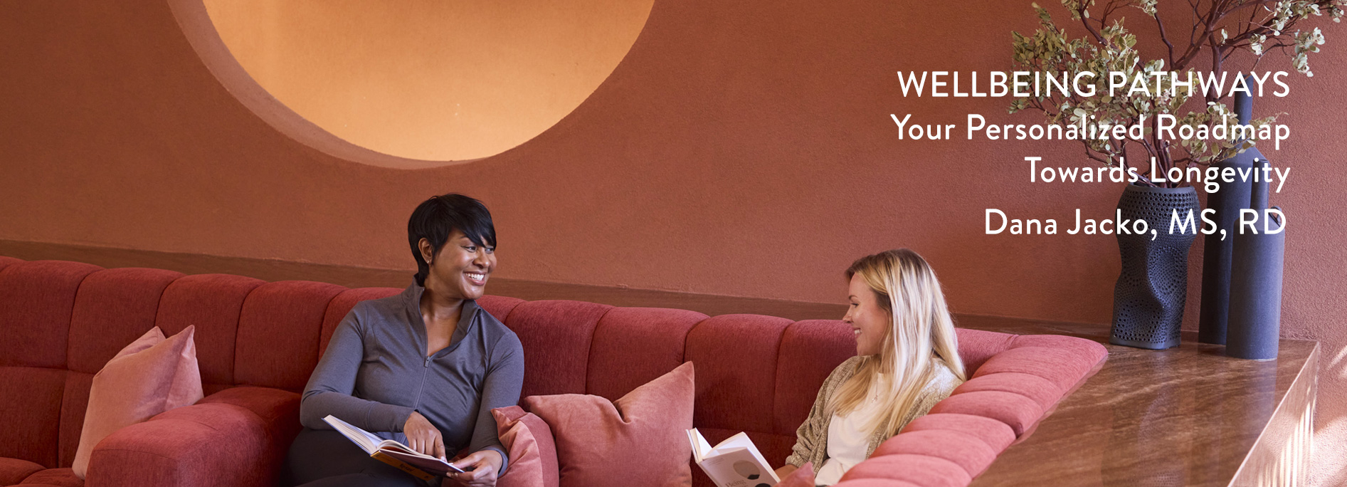 Longevity Wellbeing Pathway Header image with 2 women talking on red couch