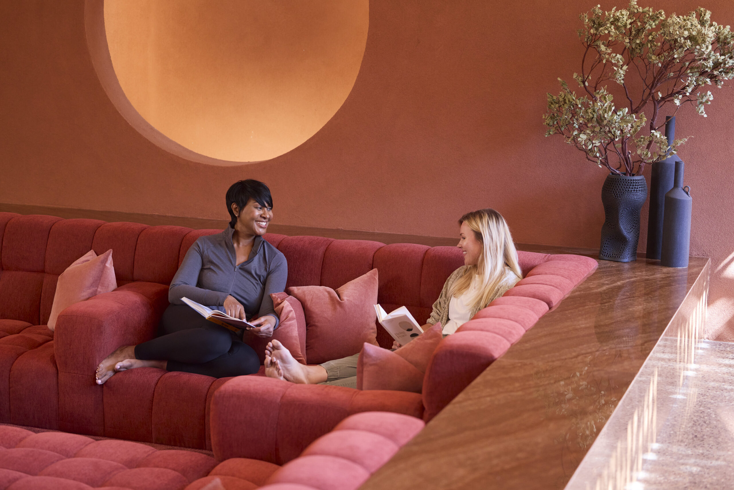 two women talking on red couch