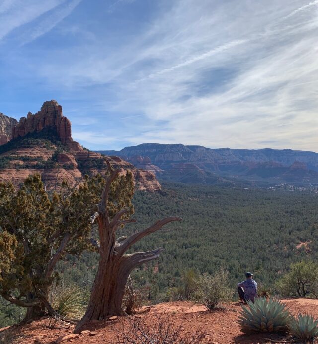 man meditating on red rocks with view