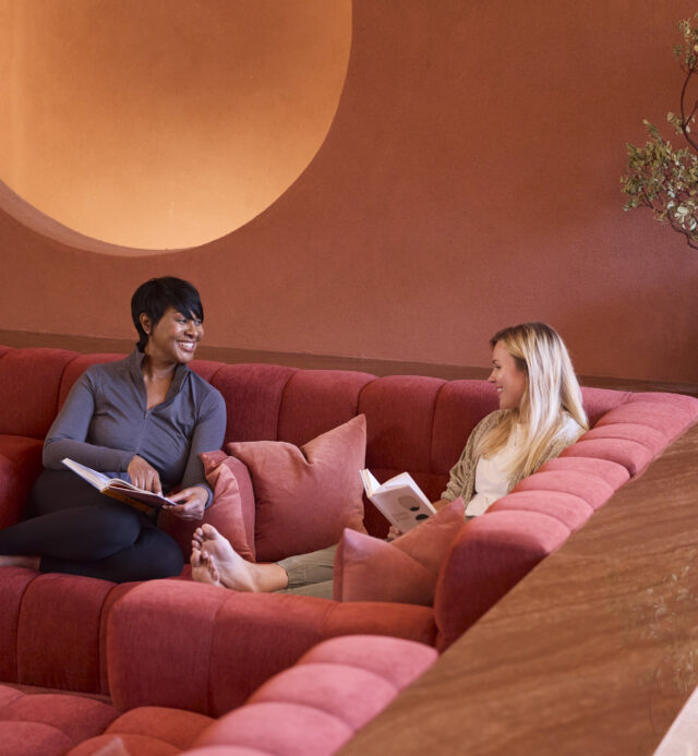 two women talking on red couch