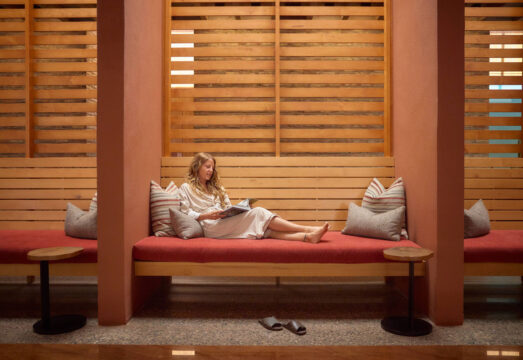 woman in robe journaling on red couch